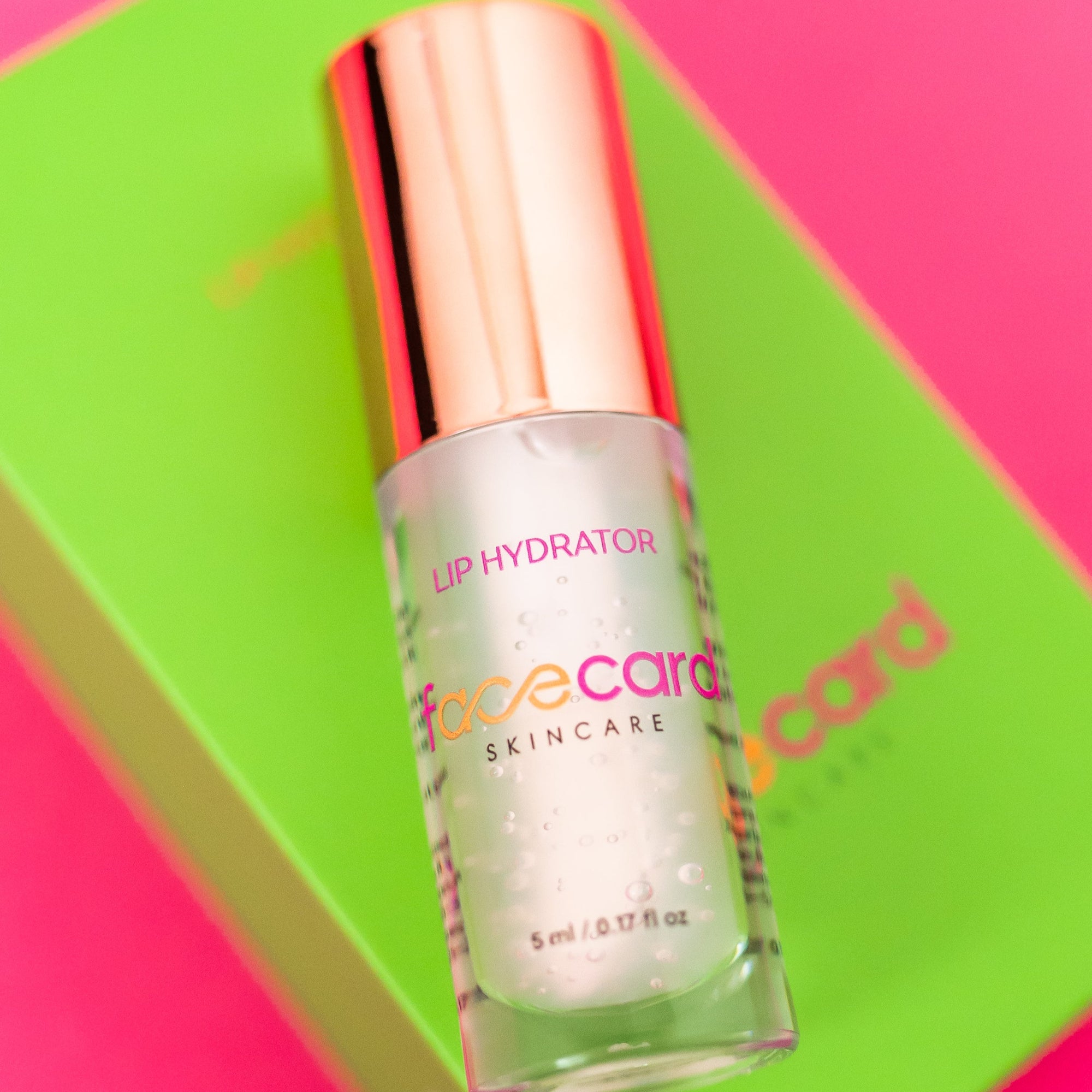 Lip hydrator bottle with pink cap on a colorful background